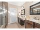 Dual sink bathroom featuring dark cabinetry, stone countertops, black framed mirrors, and a glass enclosed shower at 113 Palladium Ct, Elon, NC 27244
