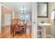 Open-concept dining area with hardwood floors, elegant chandelier, and view into the bathroom at 113 Palladium Ct, Elon, NC 27244
