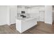 Modern kitchen with island, white cabinets, stainless steel appliances, and hardwood floors at 121 Willow Cameron Way, Angier, NC 27501
