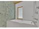 Modern bathroom with green tile, soaking tub, and wood-trimmed window for a serene, spa-like experience at 206 Spring Ln, Chapel Hill, NC 27514