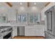 Bright kitchen featuring wood beam ceiling, stainless steel appliances, and white cabinetry with tile flooring at 206 Spring Ln, Chapel Hill, NC 27514
