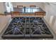 Close up of a Wolf range top with blue flames in a bright kitchen with dining space in the background at 206 Spring Ln, Chapel Hill, NC 27514