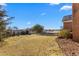 Wide shot of the home's backyard and brick exterior under a bright blue sky and scattered clouds at 2318 Rogers Rd, Graham, NC 27253
