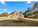 A brick house with a large yard and a garage surrounded by a sparse forest at 2318 Rogers Rd, Graham, NC 27253