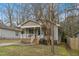 Quaint home featuring a covered front porch, neutral siding, and mature trees at 2513 Drexall Ave, Durham, NC 27704