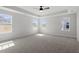 This bedroom has carpet, a ceiling fan, tray ceiling, and large windows with views of the community at 319 N Maple Walk # 213, Garner, NC 27529