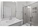 White bathroom vanity with a gray countertop, sink and tile shower with glass doors at 322 N Maple Walk Walk # 237, Garner, NC 27529