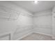 Spacious walk-in closet with adjustable white shelving, neutral colored carpet, and a convenient door at 322 N Maple Walk Walk # 237, Garner, NC 27529