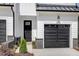 Close up exterior of a townhome, featuring a black front door and a black garage door at 4095 Elk Crk Ln, Raleigh, NC 27612
