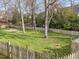 A spacious, grassy backyard with a weathered fence, mature trees, and a seating area at 4745 Grand Cypress Ct, Raleigh, NC 27604