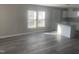 Bright living room featuring hardwood floors, two large windows, and an open floor plan flowing into the kitchen area at 523 E Nelson Ave, Wake Forest, NC 27587
