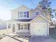 Charming two-story home featuring a covered porch, attached garage and neutral siding against a bright blue sky at 543 Camel St, Clayton, NC 27520