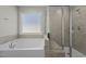 Bright bathroom with a window over the bathtub and a glass door shower stall at 5601 Garnet Meadow Rd, Knightdale, NC 27545
