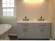 Bright bathroom featuring a double vanity with modern fixtures and a soaking tub beneath a window at 5780 Plain View Hwy, Dunn, NC 28334