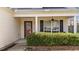Close-up of the front porch featuring a red door, ceiling fan, and lush green hedges at 613 Holly Thorn Trce, Holly Springs, NC 27540