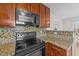 Kitchen features granite countertops, mosaic backsplash, black appliances, and wood cabinets at 613 Holly Thorn Trce, Holly Springs, NC 27540