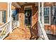 Charming front porch featuring brick flooring, white railings, and a welcoming wreath on the black front door at 6320 Bayswater Trl, Raleigh, NC 27612