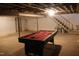View of the unfinished basement featuring a pool table, stairwell, and utility access at 7414 Virgilina Rd, Roxboro, NC 27574
