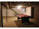 Unfinished basement area showcasing a pool table and access to the upper level staircase at 7414 Virgilina Rd, Roxboro, NC 27574