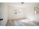 Bright bedroom featuring two windows, light gray floors, and white walls at 7414 Virgilina Rd, Roxboro, NC 27574