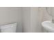 A half bathroom with a white toilet, a sink with chrome fixtures, and a round mirror at 99 Paper Birch Way, Fuquay Varina, NC 27526