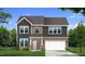Charming two-story home showcasing a gray exterior, brick accents, and a well-manicured lawn at 1020 Channel Drop Lp, Zebulon, NC 27597
