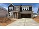 Two-story home with a mix of brick and dark siding, featuring a two-car garage and a covered front entrance at 1020 Channel Drop Lp, Zebulon, NC 27597