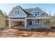 Charming two-story home featuring a welcoming front porch, attached garage, and light blue siding at 104 Pointe Park Cir, Holly Springs, NC 27540