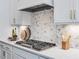 Close up on a modern kitchen featuring a stainless steel gas cooktop and mosaic backsplash at 104 Pointe Park Cir, Holly Springs, NC 27540