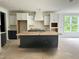 Modern kitchen with white cabinetry, dark island, and stainless steel appliances to be installed at 104 Pointe Park Cir, Holly Springs, NC 27540