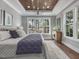 Serene main bedroom with wood tray ceiling, large windows, and stylish furnishings at 104 Pointe Park Cir, Holly Springs, NC 27540