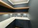 Well-organized pantry with dark blue cabinets, light countertops, and open wooden shelving for optimal storage at 104 Pointe Park Cir, Holly Springs, NC 27540