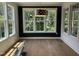 Bright sunroom with hardwood floors, large windows, wainscoting, and views of the surrounding trees at 104 Pointe Park Cir, Holly Springs, NC 27540