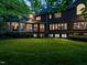 Evening view of a spacious backyard with a brick home exterior and illuminated sunroom at 107 Marseille Pl, Cary, NC 27511