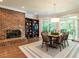 Elegant dining room with a brick fireplace, wood floors, and bright windows overlooking the lush yard at 107 Marseille Pl, Cary, NC 27511