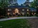 An impressive brick home at twilight featuring manicured landscaping and an inviting arched entryway at 107 Marseille Pl, Cary, NC 27511