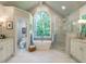 Luxurious bathroom with tub under arched window and walk-in shower, bright with double sink vanity at 107 Marseille Pl, Cary, NC 27511