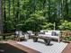 Relaxing outdoor patio with comfortable seating, striped rug, and beautiful woodland views at 107 Marseille Pl, Cary, NC 27511
