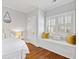 Bright bedroom features hardwood floors, white walls, shutters, and a window bench at 1200 Glenwood Ave, Raleigh, NC 27605
