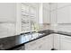 A well-lit kitchen features modern stainless steel sink, subway tile backsplash, and white cabinetry at 1200 Glenwood Ave, Raleigh, NC 27605