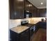 Modern kitchen boasts dark cabinets, granite countertops, stainless steel appliances, and tiled backsplash at 1520 Village Grove Ct, Hillsborough, NC 27278
