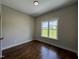 Bright bedroom featuring wood floors, neutral walls, and a window overlooking a green lawn at 165 Cotton Fields Ln # 25, Fuquay Varina, NC 27526