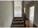 Hallway featuring carpeted stairs, a wood handrail, and a view into a neutral carpeted room at 165 Cotton Fields Ln # 25, Fuquay Varina, NC 27526