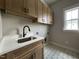 Well-lit laundry room featuring overhead cabinets, a modern sink and stylish tile floors at 165 Cotton Fields Ln # 25, Fuquay Varina, NC 27526