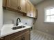 Charming laundry room with patterned tile, ample cabinets, and a stainless steel sink beneath a window at 165 Cotton Fields Ln # 25, Fuquay Varina, NC 27526
