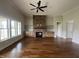 Cozy living room featuring hardwood floors, a stone fireplace, and large windows for natural light at 165 Cotton Fields Ln # 25, Fuquay Varina, NC 27526