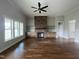 Spacious living room featuring hardwood floors, a stone fireplace, and large windows at 165 Cotton Fields Ln # 25, Fuquay Varina, NC 27526
