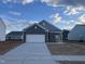 Charming single-story home with a gray facade, a two-car garage, and a concrete driveway under a partially cloudy sky at 264 Logan Creek Dr, Zebulon, NC 27597