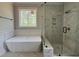 A luxurious bathroom features a soaking tub, frameless shower, vanity, and marble-look tile at 309 Deer Tail Ln # 42, Fuquay Varina, NC 27526