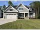 Charming two-story home with gray siding, stone accents, a manicured lawn and a three car garage at 309 Deer Tail Ln # 42, Fuquay Varina, NC 27526